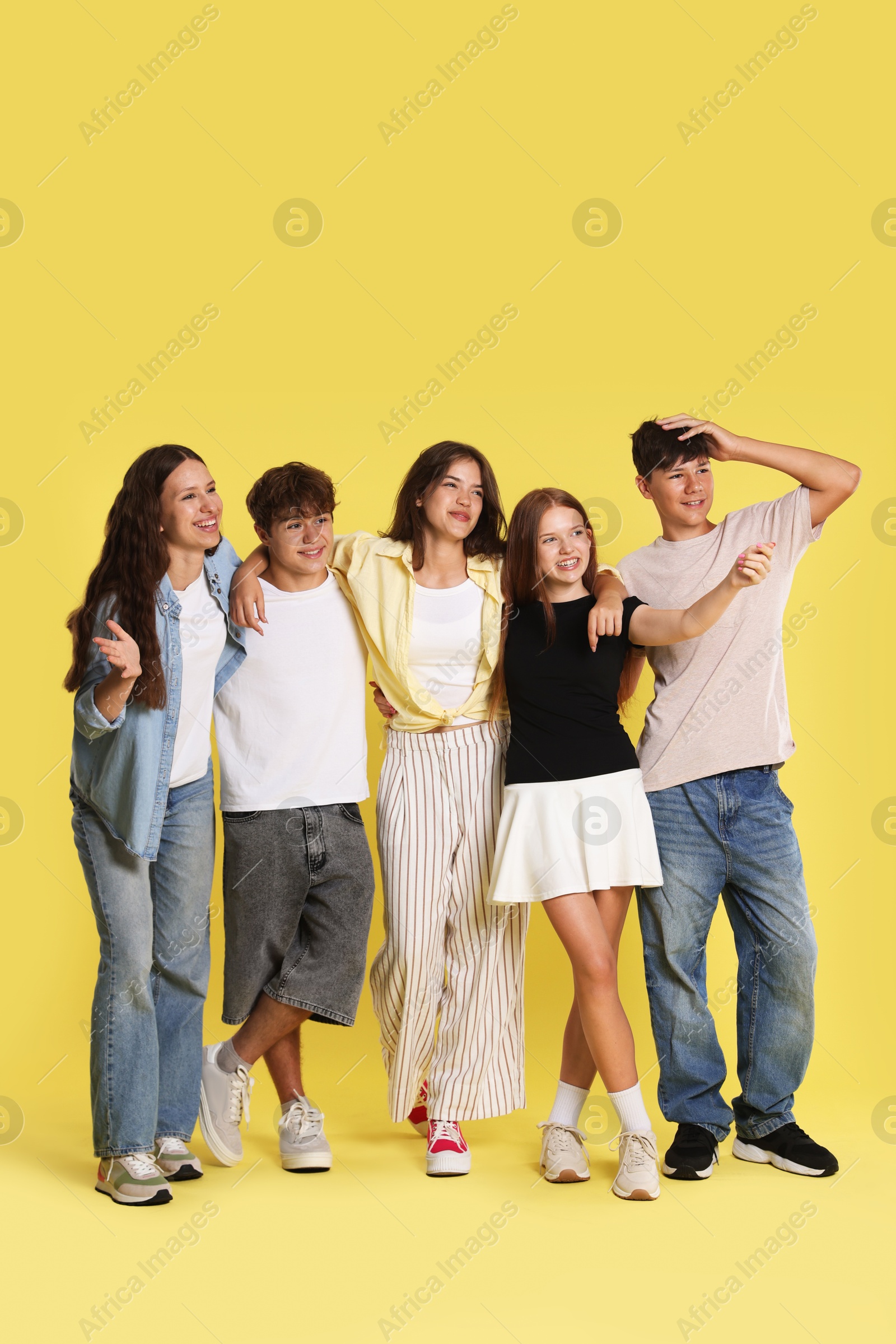Full-length portrait of happy teenage friends on yellow background Photo of Full-length portrait of happy teenage friends on yellow background