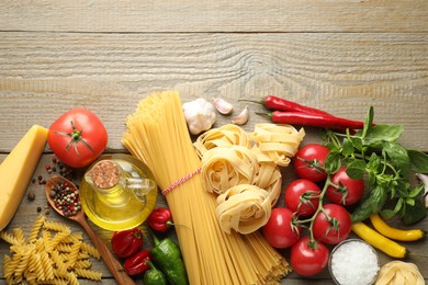 Photo of Different types of pasta and ingredients on wooden table, flat lay. Space for text