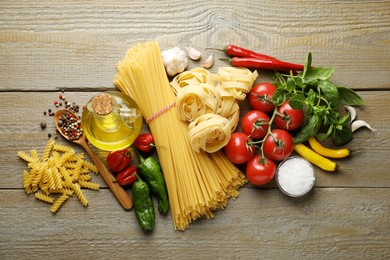 Photo of Different types of pasta and ingredients on wooden table, flat lay