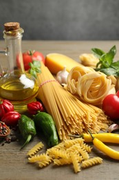 Photo of Different types of pasta and ingredients on wooden table, closeup