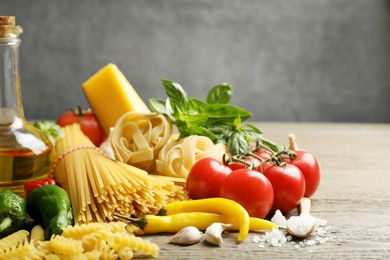 Photo of Different types of pasta and ingredients on wooden table, closeup