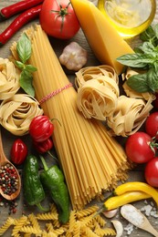 Photo of Different types of pasta and ingredients on wooden table, flat lay