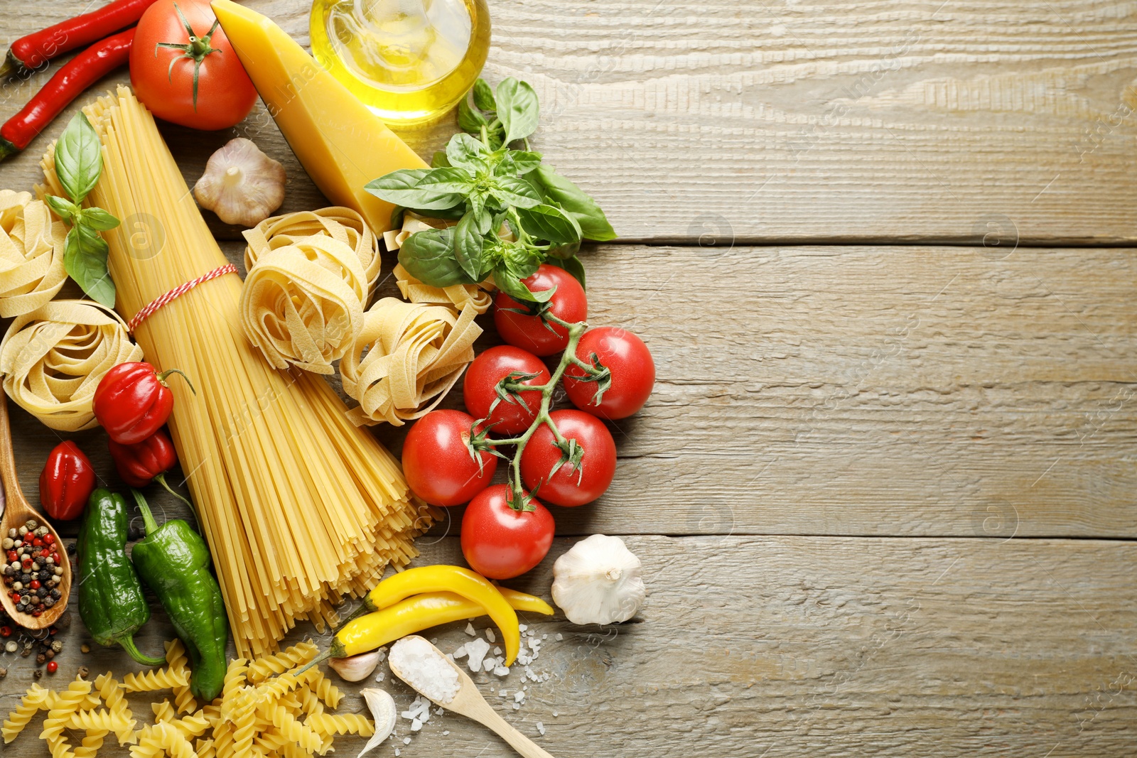 Different types of pasta and ingredients on wooden table, flat lay. Space for text Photo of Different types of pasta and ingredients on wooden table, flat lay. Space for text