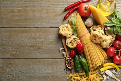 Photo of Different types of pasta and ingredients on wooden table, flat lay. Space for text