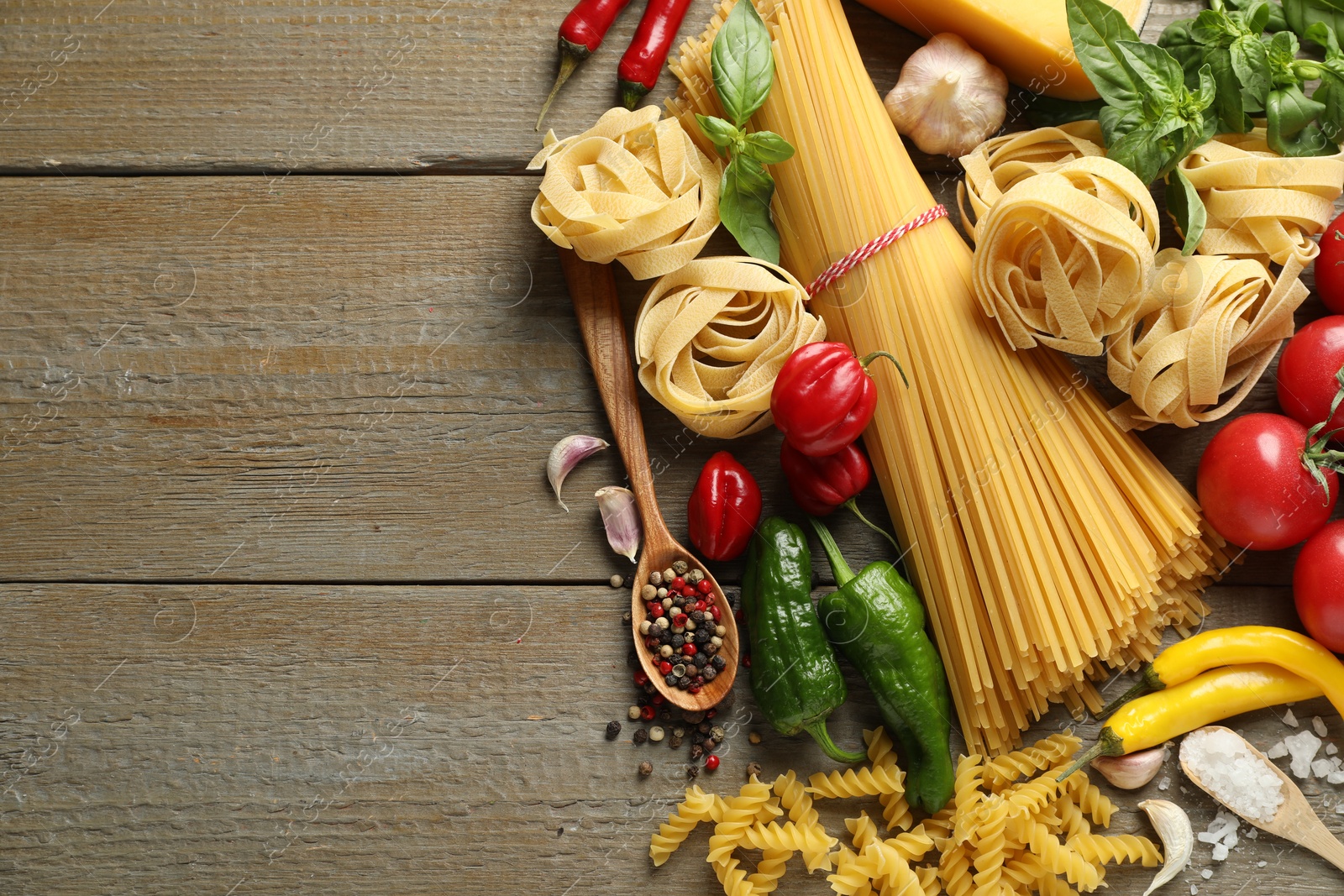 Different types of pasta and ingredients on wooden table, flat lay. Space for text Photo of Different types of pasta and ingredients on wooden table, flat lay. Space for text