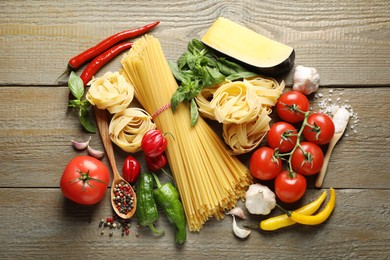 Photo of Different types of pasta and ingredients on wooden table, flat lay