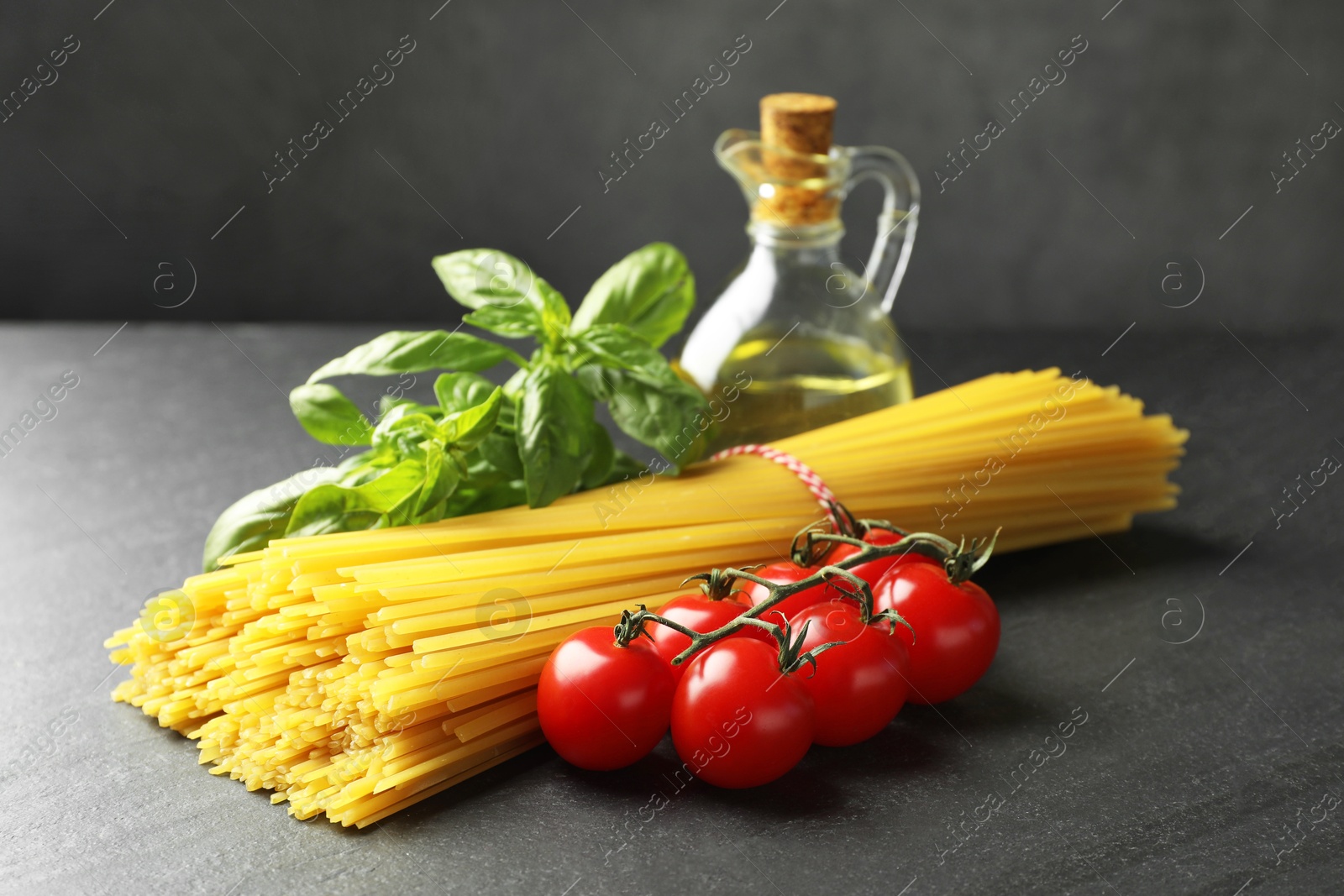 Raw spaghetti pasta and different ingredients on black table, closeup Photo of Raw spaghetti pasta and different ingredients on black table, closeup