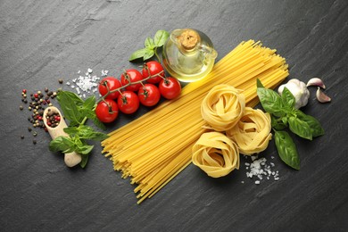 Photo of Different types of pasta and ingredients on black table, flat lay