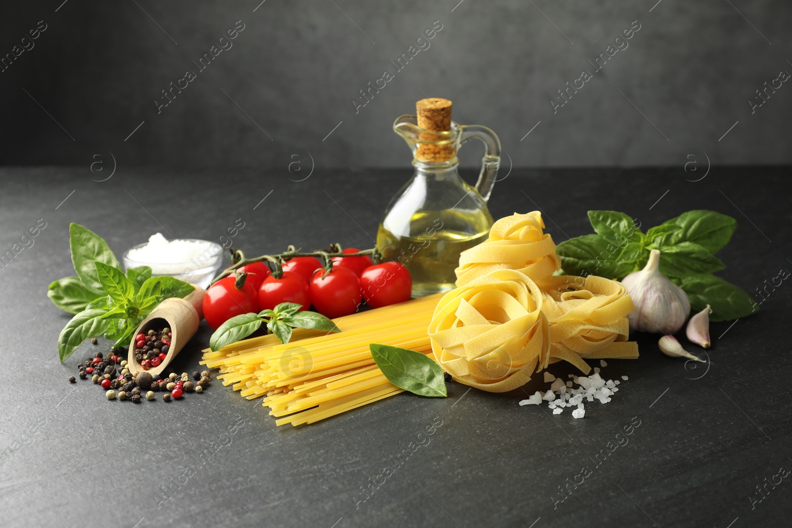 Different types of pasta and ingredients on black table Photo of Different types of pasta and ingredients on black table