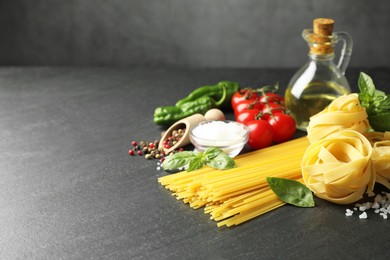 Photo of Different types of pasta and ingredients on black table, closeup. Space for text