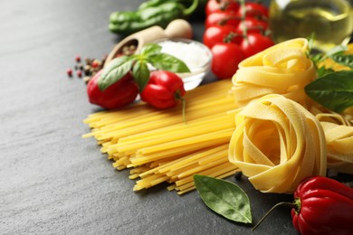 Photo of Different types of pasta and ingredients on black table, closeup. Space for text