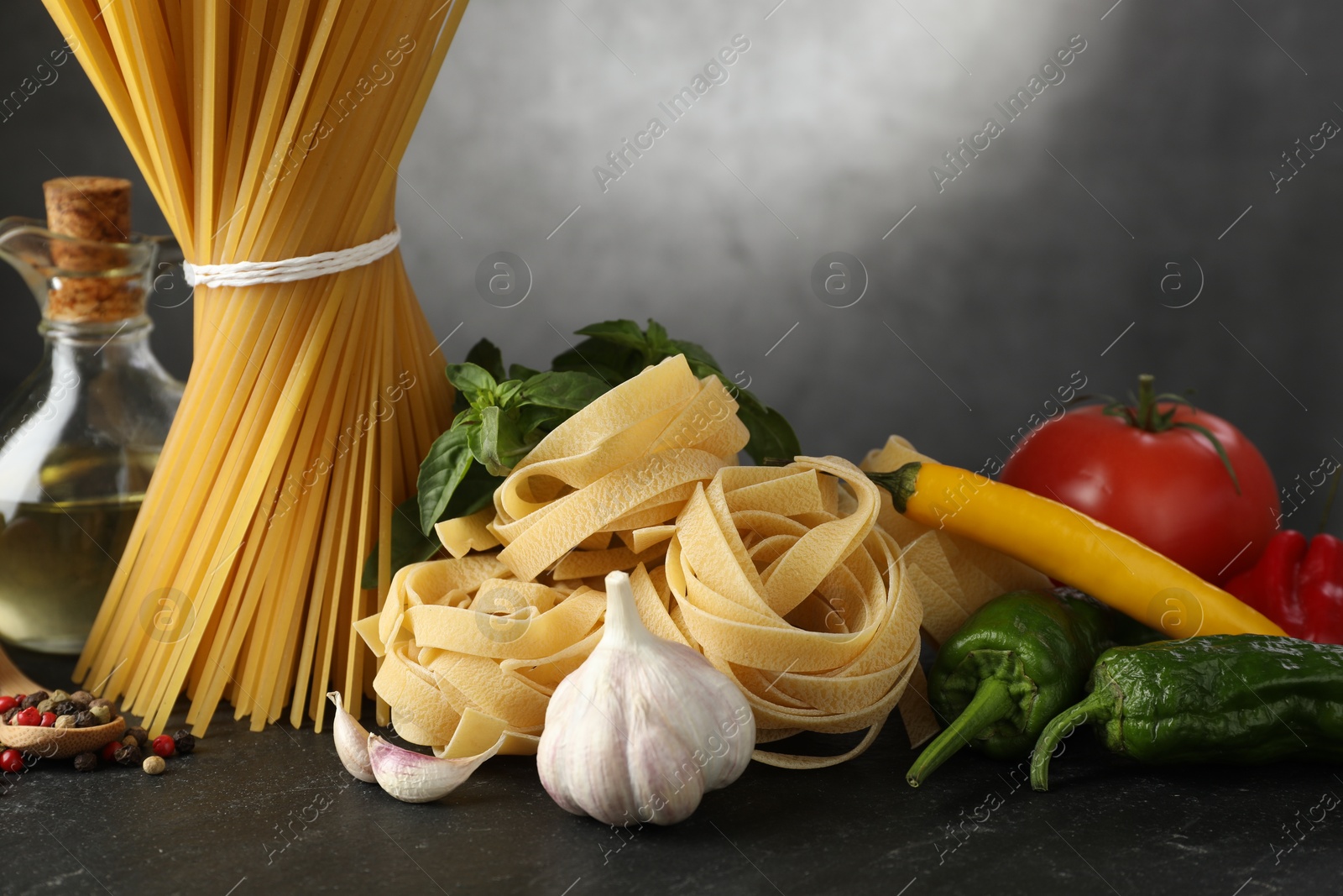 Different types of pasta and ingredients on black table, closeup Photo of Different types of pasta and ingredients on black table, closeup