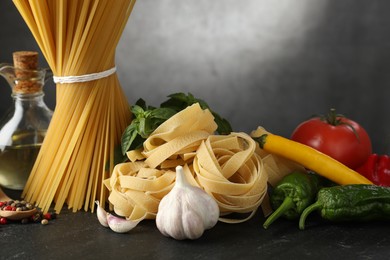 Photo of Different types of pasta and ingredients on black table, closeup