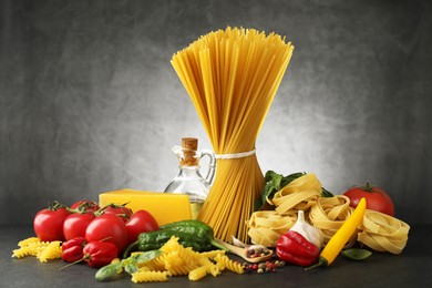 Photo of Different types of pasta and ingredients on black table