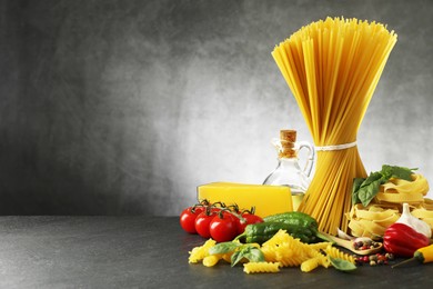 Photo of Different types of pasta and ingredients on black table, space for text