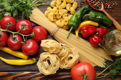 Photo of Different types of pasta and ingredients on wooden table, flat lay