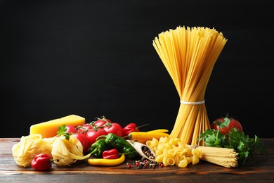 Photo of Different types of pasta and ingredients on wooden table