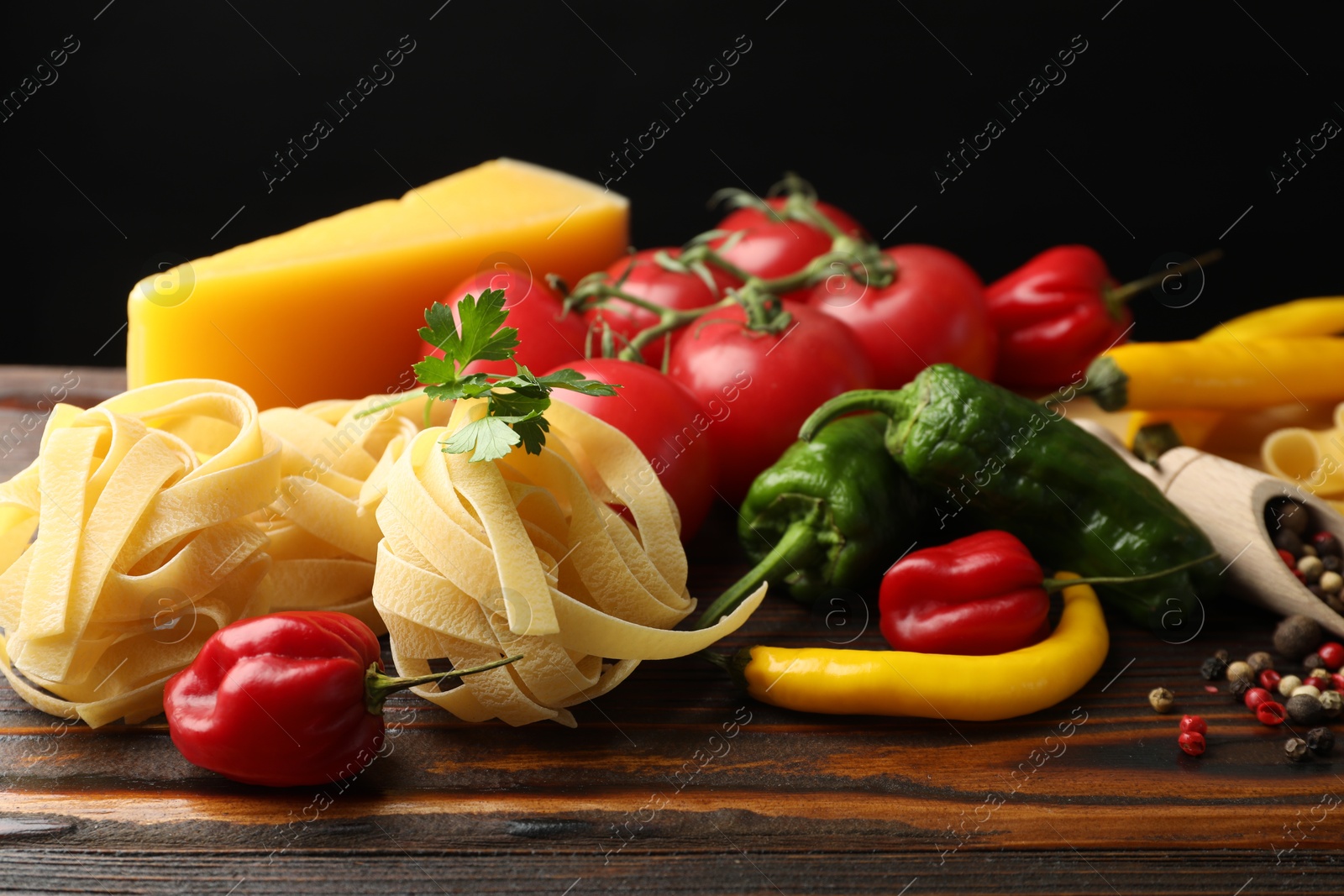Raw tagliatelle pasta and different ingredients on wooden table, closeup Photo of Raw tagliatelle pasta and different ingredients on wooden table, closeup