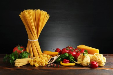 Photo of Different types of pasta and ingredients on wooden table