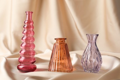 Photo of Different beautiful glass vases on beige cloth