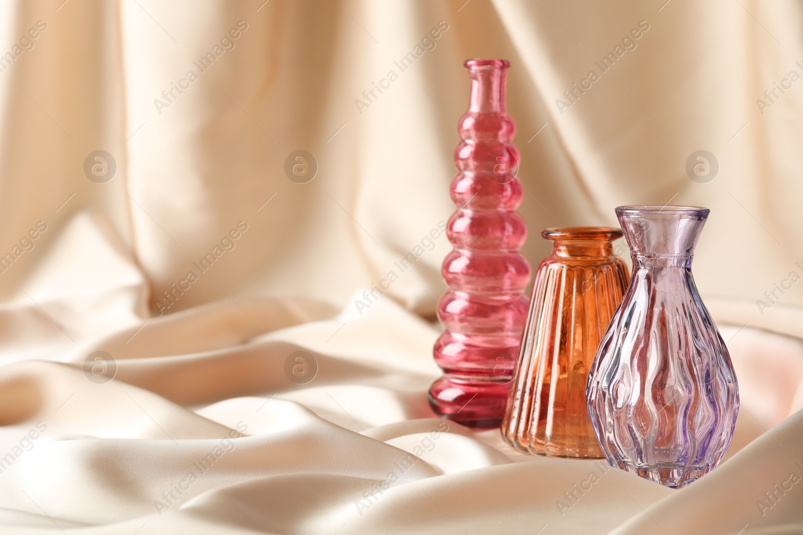 Photo of Different beautiful glass vases on beige cloth, space for text