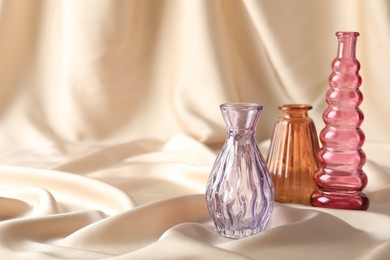 Photo of Different beautiful glass vases on beige cloth, space for text