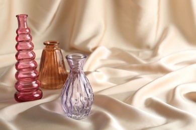 Photo of Different beautiful glass vases on beige cloth, space for text