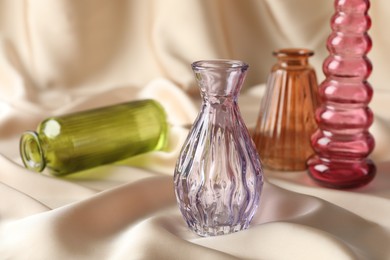 Photo of Different beautiful glass vases on beige cloth, space for text