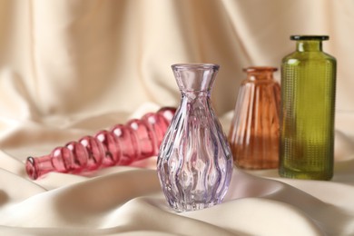 Photo of Different beautiful glass vases on beige cloth, space for text
