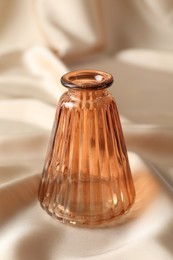 Photo of One beautiful glass vase on beige cloth, closeup