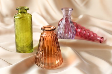 Photo of Different beautiful glass vases on beige cloth, closeup. Space for text