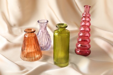 Photo of Different beautiful glass vases on beige cloth