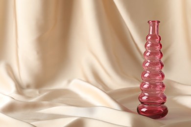 Photo of One beautiful glass vase on beige cloth, space for text