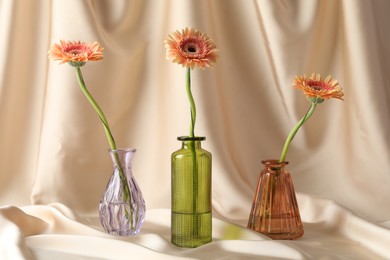 Photo of Beautiful flowers in glass vases on beige cloth