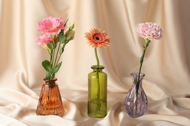Photo of Beautiful flowers in glass vases on beige cloth