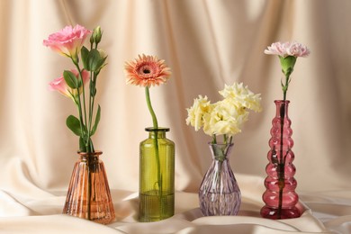 Photo of Beautiful flowers in glass vases on beige cloth