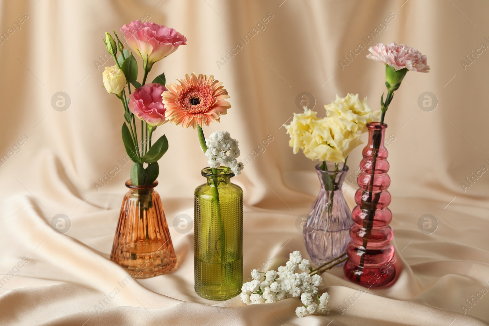 Beautiful flowers in glass vases on beige cloth Photo of Beautiful flowers in glass vases on beige cloth