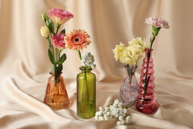 Photo of Beautiful flowers in glass vases on beige cloth