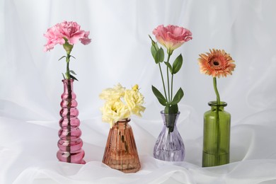 Photo of Beautiful flowers in glass vases on white cloth