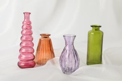 Photo of Different beautiful glass vases on white cloth