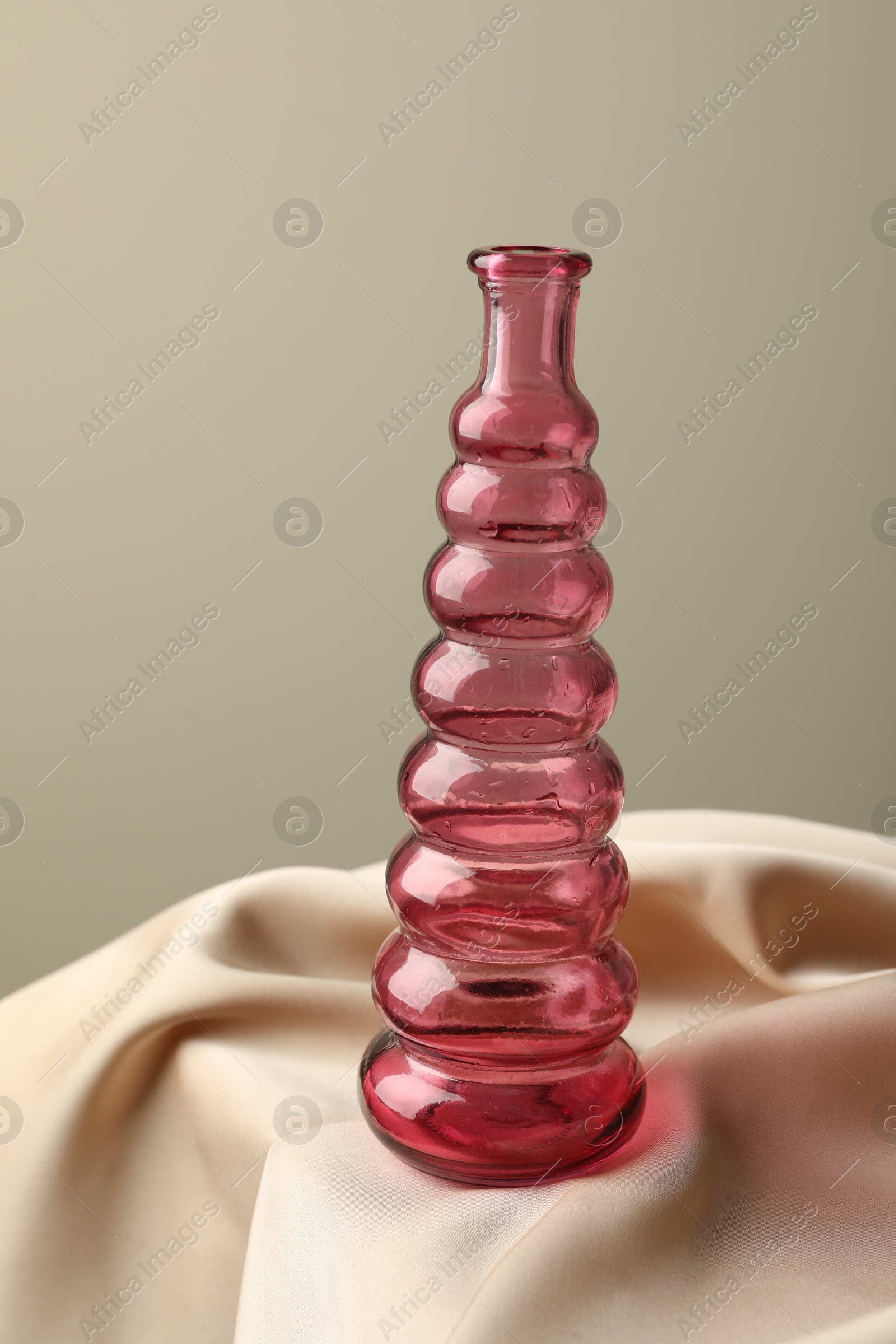 One beautiful glass vase on beige cloth against light background, closeup Photo of One beautiful glass vase on beige cloth against light background, closeup