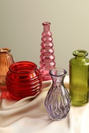 Photo of Different beautiful glass vases on beige cloth against light background, closeup