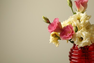 Photo of Beautiful flowers in glass vase on beige background, closeup. Space for text