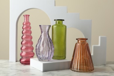 Photo of Different beautiful glass vases on white marble table against beige background