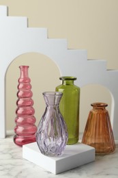 Photo of Different beautiful glass vases on white marble table against beige background, closeup