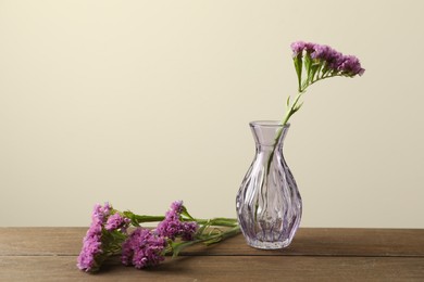 Photo of Beautiful flowers and glass vases on wooden table against beige background