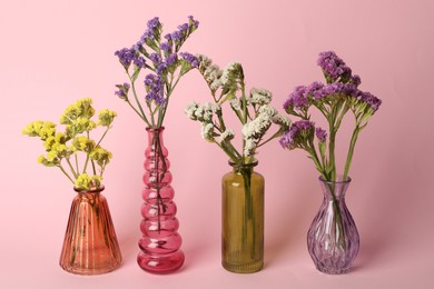 Photo of Beautiful flowers in glass vases on pink background