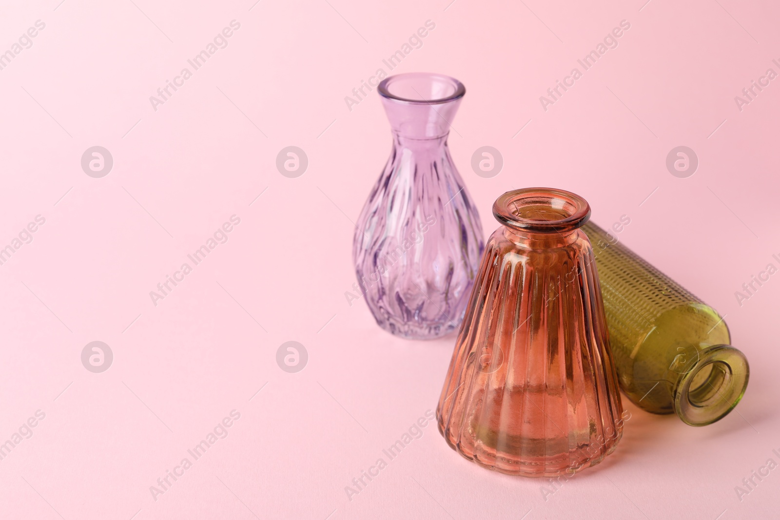 Different beautiful glass vases on pink background, closeup. Space for text Photo of Different beautiful glass vases on pink background, closeup. Space for text