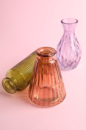 Photo of Different beautiful glass vases on pink background, closeup