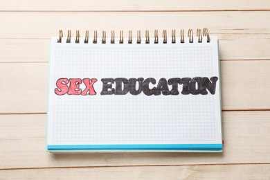 Photo of Notebook with words Sex Education on wooden table, top view